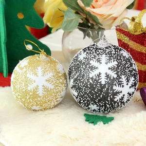 Detail of gold and black Christmas baubles with 3D foam snowflakes on white plush