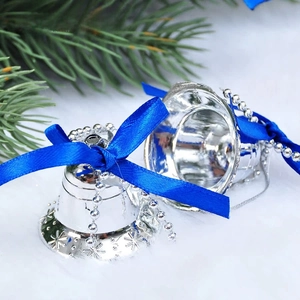 Close-up of silver Christmas bells with snowflake relief and blue satin ribbons