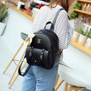 Detail eines schwarzen PU-Lederrucksacks mit Frontklappe und süßem Bärenanhänger