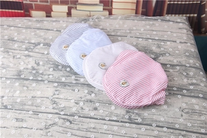 Detailed close-up of striped baby berets in red, blue, grey, and white with shield patches