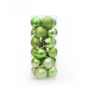Détail de boules de Noël vertes brillantes mates et pailletées dans un emballage cylindrique