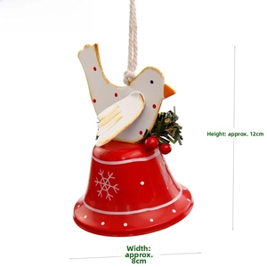 Detail of red metal bell with white bird motif and green pine needles Christmas ornament