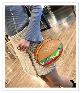 Close-up of burger-shaped crossbody bag with gold chain strap on a model's outfit