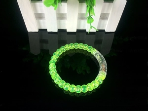Close-up of glowing green acrylic bubble bracelet with internal red decorative beads