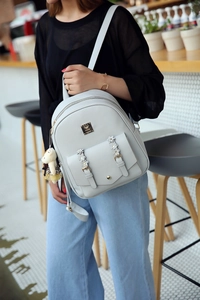 Grauer PU-Leder Rucksack mit dekorativer Vordertasche und Bärenanhänger am Model