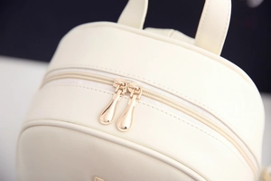 Detailaufnahme der glatten goldenen Doppelreißverschlüsse am cremefarbenen PU-Rucksack
