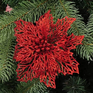 Detail of red glitter Christmas flower ornament on green pine needle background