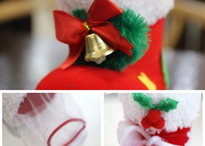 Macro detail of red plush Christmas boots with gold bell and holly leaf decorations