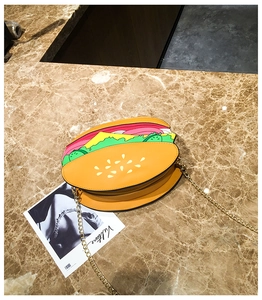 Top view of creative hamburger-shaped crossbody bag with gold chain on marble surface