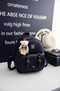 Detailansicht eines schwarzen PU-Lederrucksacks mit Metallschnalle und Teddybär-Anhänger