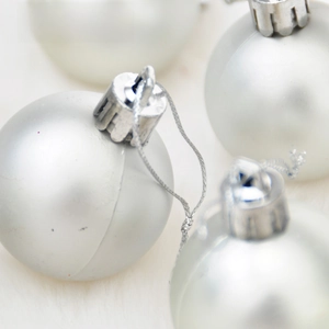 Close-up of silver matte Christmas ball with metallic cap and string on white fur