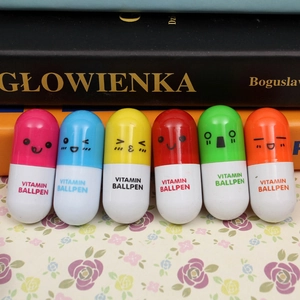 Detailed view of six colorful cartoon capsule pens with cute facial expressions on the desk