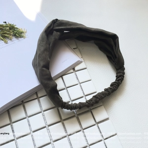 Close-up of olive green twisted knit headband showing elastic band and matte fabric texture