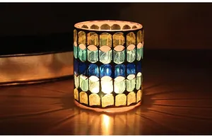 Close-up of a mosaic glass candle holder with vibrant light patterns on a dark surface