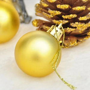 Close-up of matte gold Christmas ball ornament with hanging loop on white plush surface