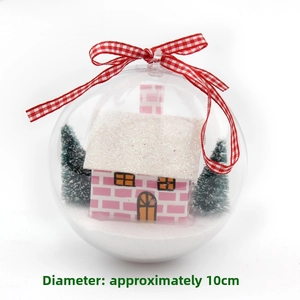 Detail of clear Christmas ball with pink house, snowy trees and red checkered ribbon bow
