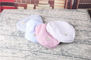 Detail of four striped baby berets in blue, pink and beige with embroidery patches