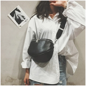 Detail view of black leather half-moon crossbody bag styled on a white shirt and jeans