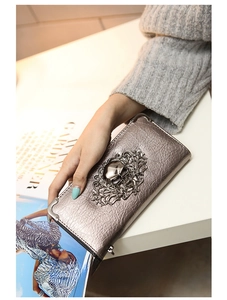 Detail of silver skull embossed leather wallet with metallic corners and floral patterns