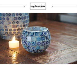 Blue and white mosaic glass candle holder on wooden table with daytime lighting