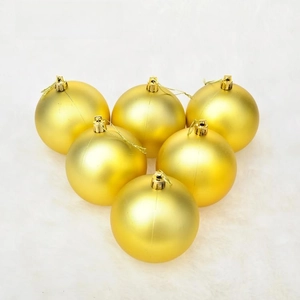 Detail of six matte gold Christmas ball ornaments arranged on white faux fur background