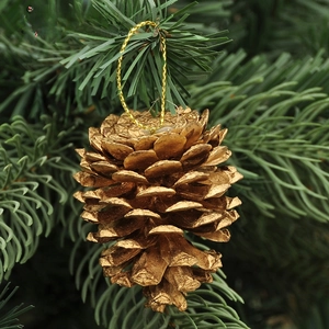 Dettaglio di una pigna dorata con cordino su un ramo di un albero di Natale