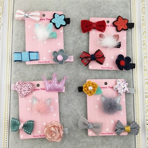 Detail view of pink bow, sequin star, and mink fur crown hair clips on a card display