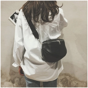 Close-up of a stylish black leather crossbody bag with wide strap on a model