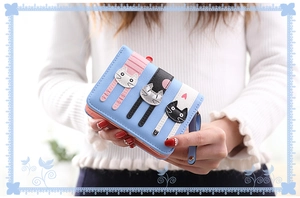 Close-up of light blue small wallet with cute three-cat patches and secure zipper closure
