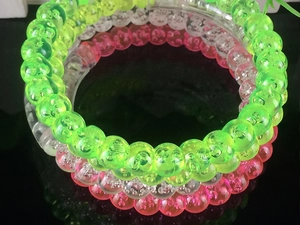 Close-up of colorful acrylic bubble bracelets with LED beads in green, pink, and clear tones