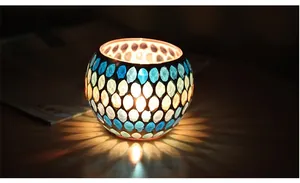 Detail of mosaic glass candle holder showing colorful light patterns on dark wood table