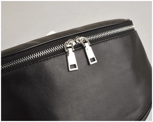 Detail of silver dual metal zippers on minimalist black leather crossbody chest bag