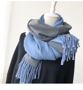 Detail of blue and grey cashmere-feel scarf showing soft knit texture and long tassels