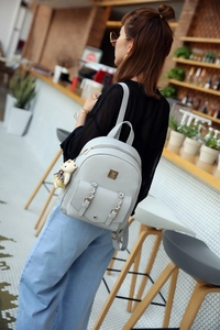 Detailansicht grauer PU-Lederrucksack mit Blumenschnalle und Bären-Taschenanhänger