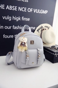 Nahaufnahme eines hellgrauen PU-Lederrucksacks mit Blumenakzenten und Bärenanhänger
