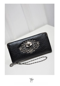 Close-up of black punk wallet with silver skull emblem and embossed floral metal hardware