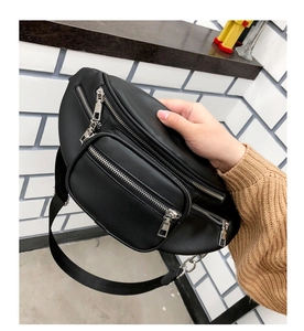 Detail of a black leather fanny pack with multi-zipper compartments and adjustable strap