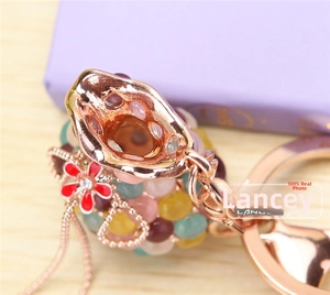 Gros plan de perles multicolores et porte-clés en métal or rose avec pendentif floral