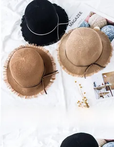 Close-up of children's woven straw hats with fringed edges and decorative bow details