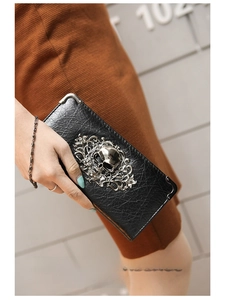 Close-up of gothic skull and baroque floral metal relief on black lychee leather wallet