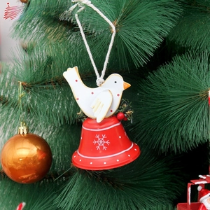 Detail of red metal bell with white snowflake pattern and bird on a Christmas tree