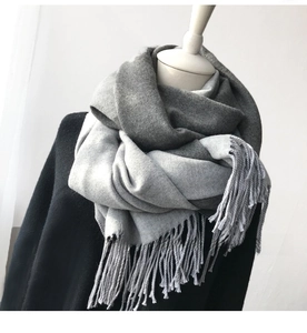 Detailed texture of thick grey cashmere-like scarf with fringe tassels on model