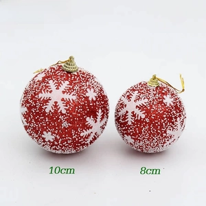 Close-up of red Christmas ornaments with white snowflake patterns and gold hangers