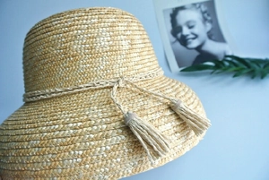 Close-up of a straw bucket hat featuring fine weave textures and elegant tassel details