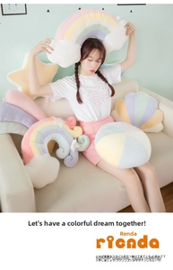 Detail of macaron-colored plush pillows including rainbow, star, and shell shapes on a sofa