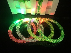 Macro shot of colorful LED light-up acrylic bubble bracelets glowing in dark party setting
