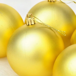 Macro shot of gold matte Christmas ornaments on white faux fur background decoration