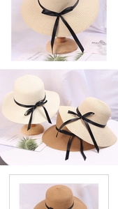 Detail of wide brim straw sun hat with black ribbon bow on wooden stand display