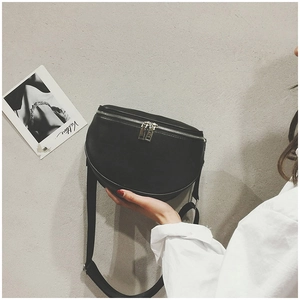 Detail view of black semi-circular crossbody bag with silver zippers and wide strap