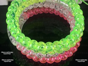Close-up of glowing acrylic bubble bracelets in neon green, pink, and clear white tones